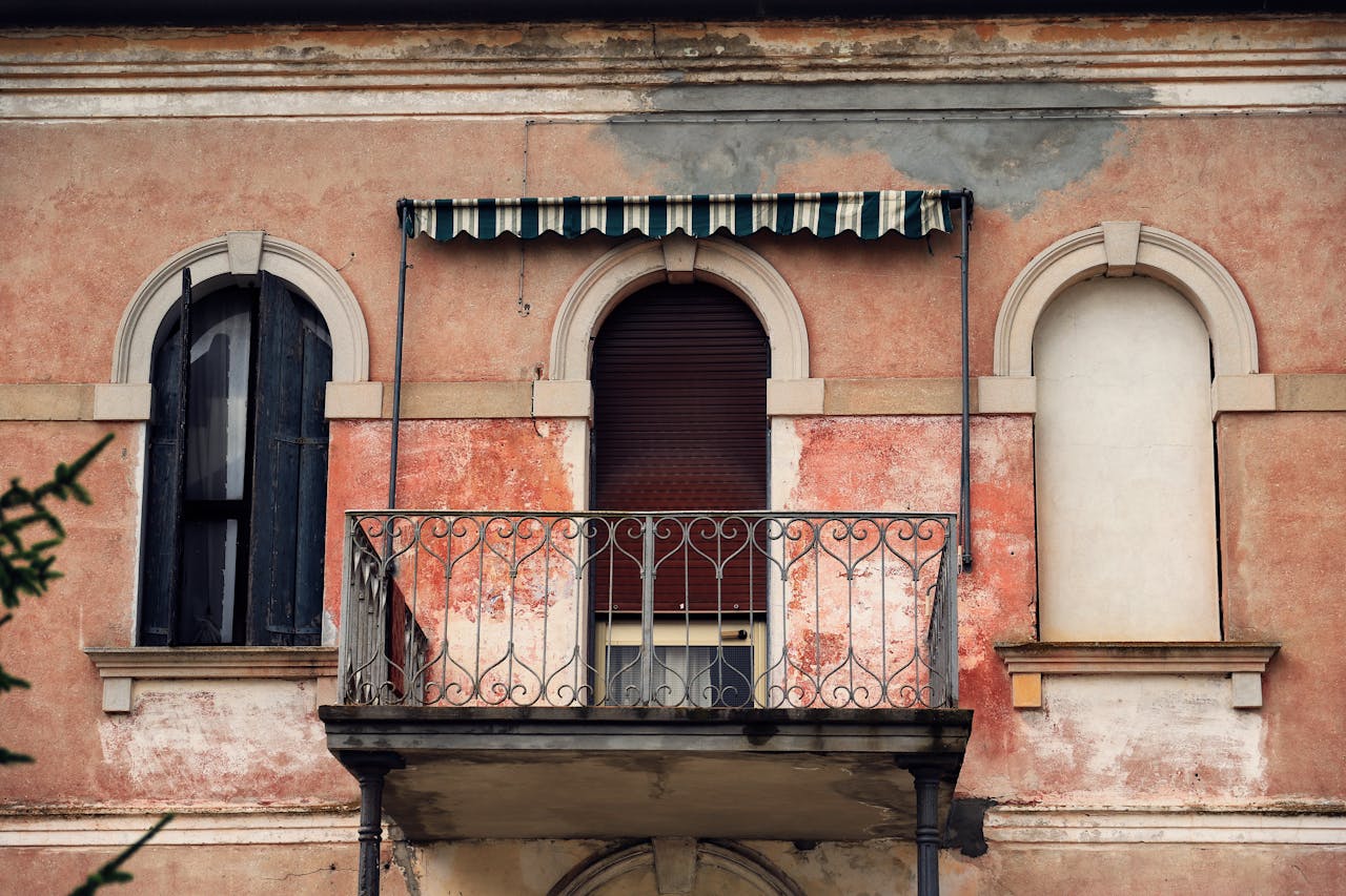 Elegant vintage Italian facade with balcony and arched windows reflecting classic architecture.